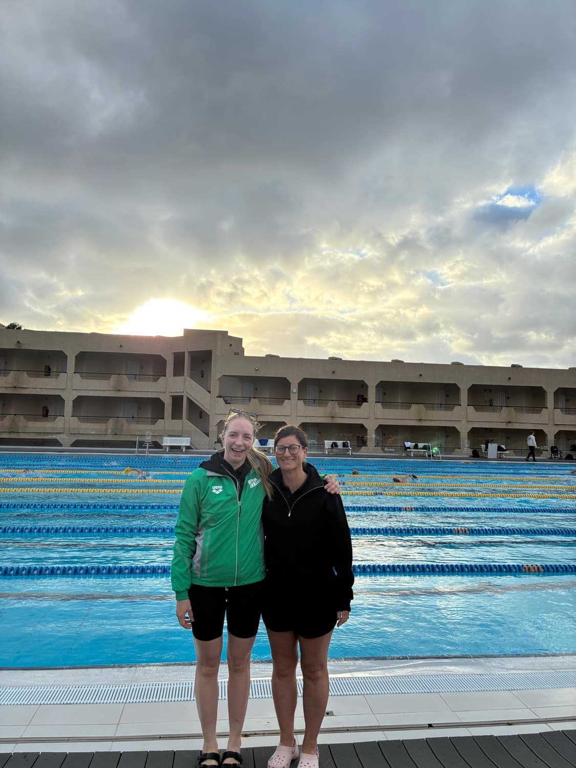 Eimear Keane poolside at sunset beside a 50m competition pool in Ireland team kit