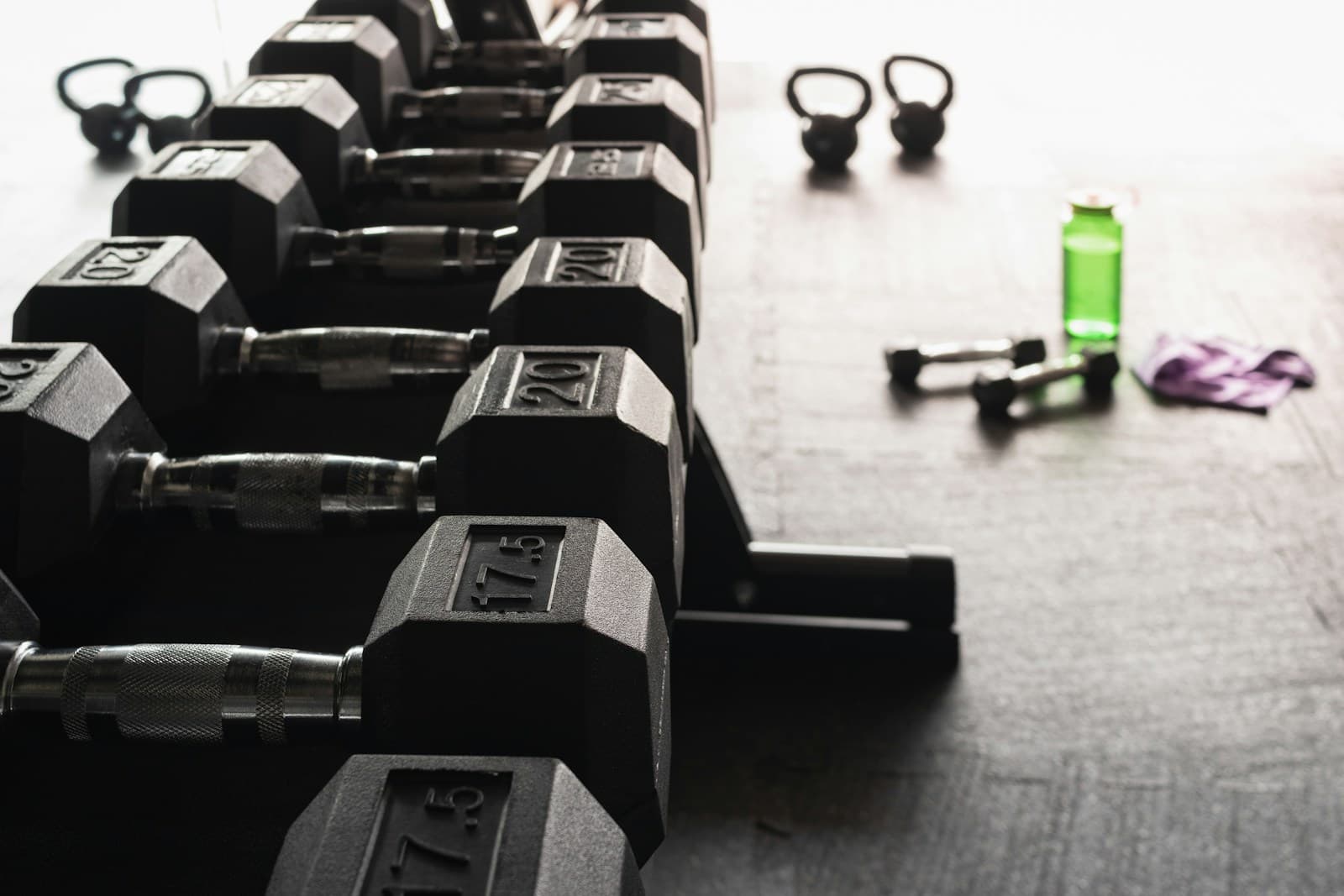 Black and grey dumbbells resting on a gym floor — strength training equipment